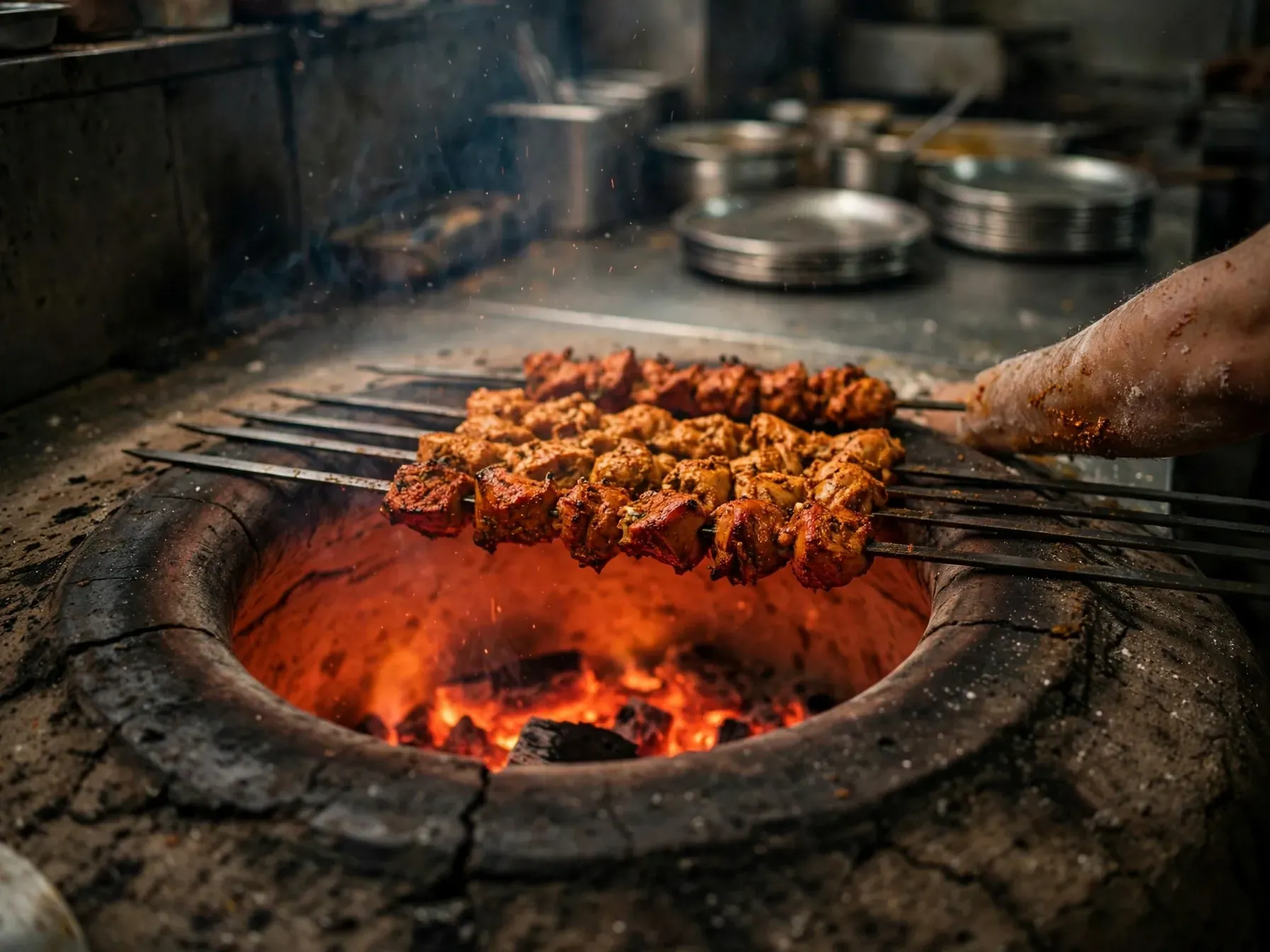 Skewers of kebab over the glowing mouth of the clay tandoor